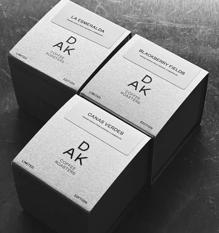 Três caixas de café da DAK Coffee Roasters, em preto e branco