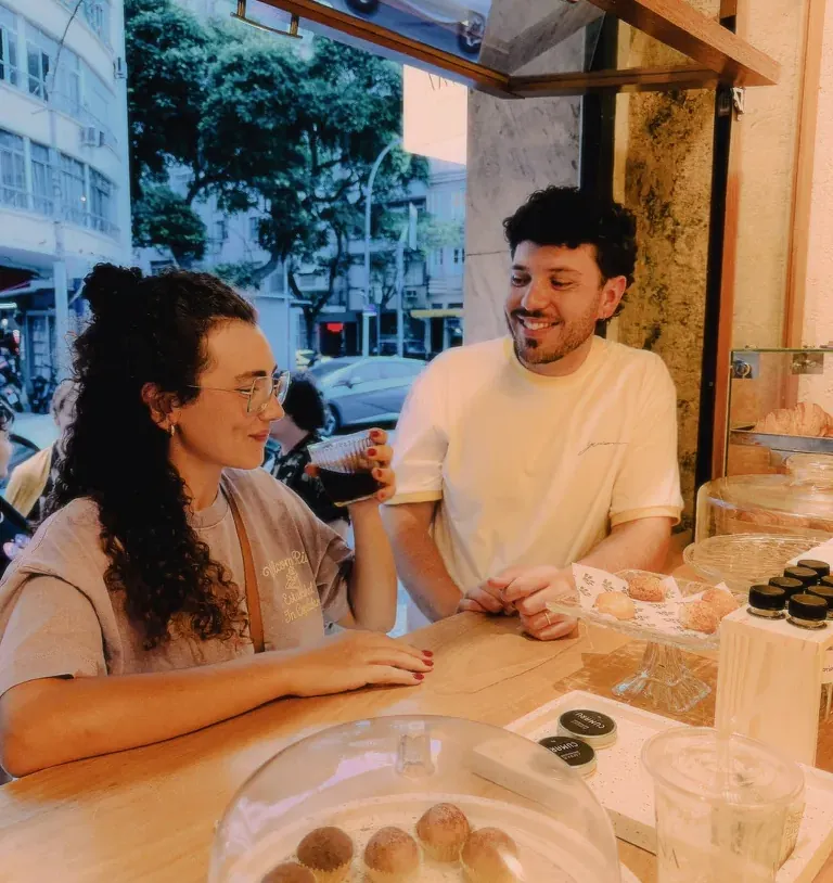 Leo à mesa de uma padaria, com doces e café