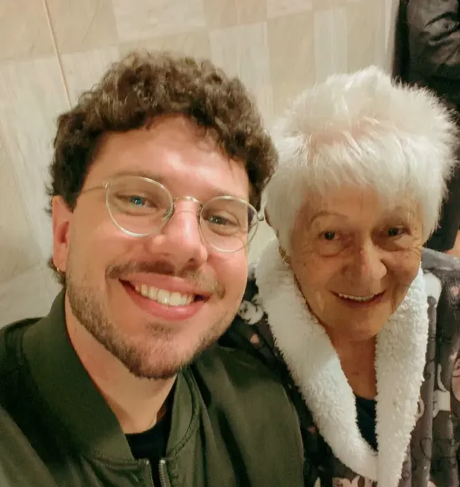Leo sorrindo ao lado de uma senhora da família