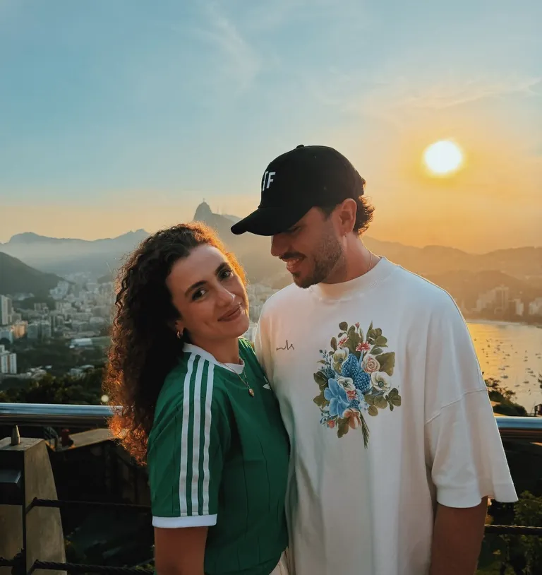 Leo e a namorada no mirante, com o Rio de Janeiro e o pôr do sol atrás